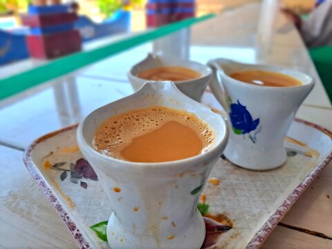 Three cups of hot masala chai tea served on a tray in an outdoor cafe