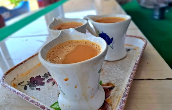 Three cups of hot masala chai tea served on a tray in a cafe setting