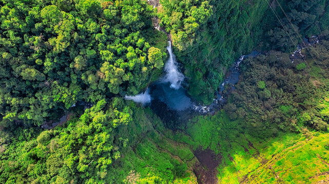 Aerial view of Tad Fane Waterfall in Laos, with a tourist enjoying tea while suspended on a zipline above the spectacular twin cascades and lush rainforest of the Bolaven Plateau.