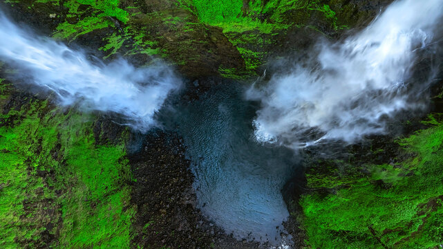 Aerial view of Tad Fane Waterfall in Laos, with a tourist enjoying tea while suspended on a zipline above the spectacular twin cascades and lush rainforest of the Bolaven Plateau.