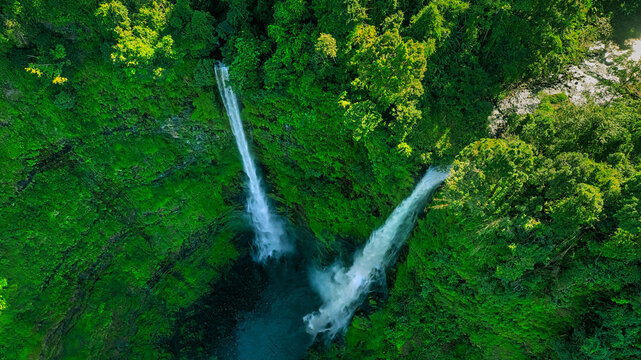 Aerial view of Tad Fane Waterfall in Laos, with a tourist enjoying tea while suspended on a zipline above the spectacular twin cascades and lush rainforest of the Bolaven Plateau.