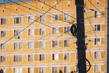 Urban scene with vibrant yellow building and tangled power lines during golden hour © Cristina