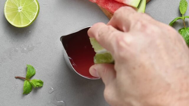 Fresh lime wedge is squeezed into watermelon juice to add bright citrus flavor to summer cocktail.