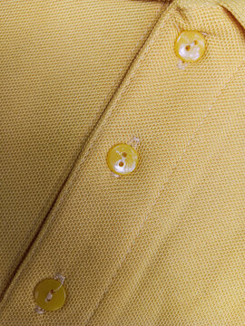 Detailed close up of buttons and stitching on a yellow polo shirt placket