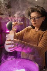 realistic witch witchcrafting brewing potion in cauldron. Everyday life intertwined with traditional witchcraft, magic and mystical atmosphere. © Andrii Lysenko