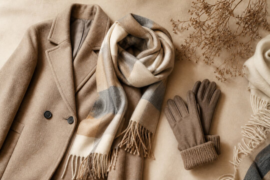 Beige coat, checked scarf and gloves laid out for a winter outfit