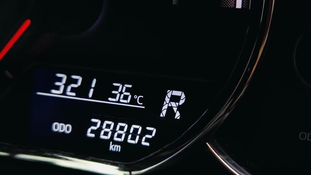 Close-up of digital car dashboard display showing reverse gear R status