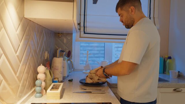 Man prepares food in a modern kitchen located in a cozy home during an evening setting