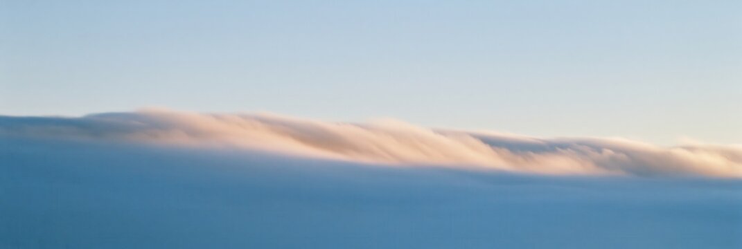 Rolling fog bank under clear sky with soft golden light