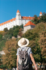 elderly tourist woman traveler looking at bratislava castle wearing hat and backpack at summer landscape background for designer template mockup concept of travel, tourism, vacation © Lana Pietukhova