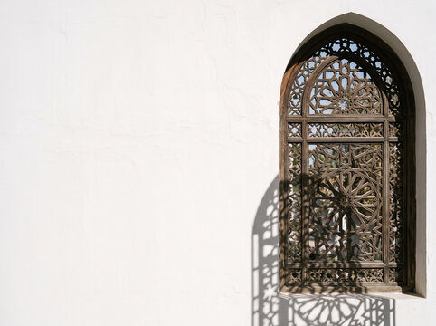 Traditional wooden mashrabiya window with intricate carved geometric patterns set in a minimalist white wall with copy space
