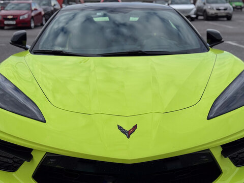 Front view of an exotic yellow Chevrolet Corvette Stingray C8 supercar. High performance american sports car with aggressive led headlights parked on a street, automotive transport traffic concept.