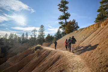 Obraz premium Tourists hiking Bryce Canyon Rim Trail. Sun rays shining through the clouds. Utah. USA.