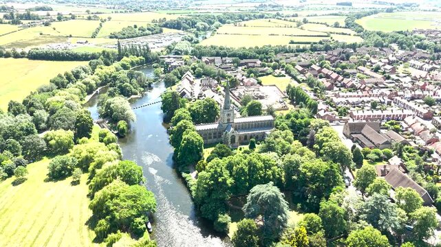 A drone captures a wide aerial view of Holy Trinity Church on the banks of the River Avon in Stratford-upon-Avon, England, the parish church where William Shakespeare is buried.