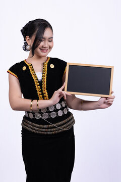 Young women wearing Kadazan-Dusun traditional attire holding a blank blackboard against a white background.