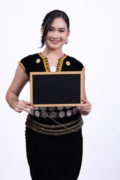 Young women wearing Kadazan-Dusun traditional attire holding a blank blackboard against a white background.