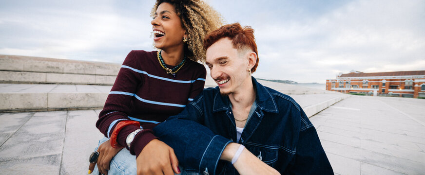 Friends laughing together outdoors by waterfront steps