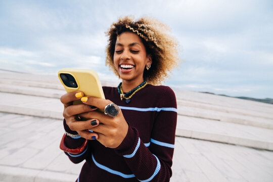 Young woman smiling and texting on the phone outdoors