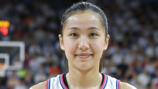 Young Female Athlete Smiling in Basketball Jersey with Courtside Background