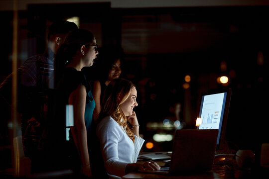 Night, team and happy woman with computer screen for graphs, viral campaign stats or ROAS target. Marketing manager, people and dashboard in office with ads engagement, KPI performance and overtime