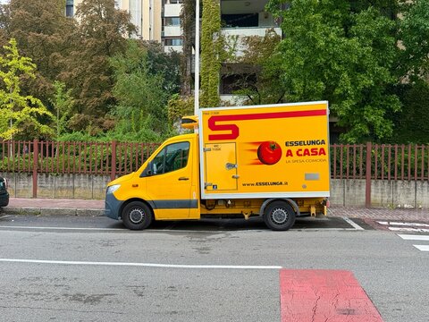 Yellow Esselunga delivery vehicle parked outside a residential property during a grocery delivery. Milan, Italy
