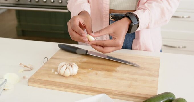 Lifestyle videos indoor of people doing activities at home, chopping garlic on board, person prepari
