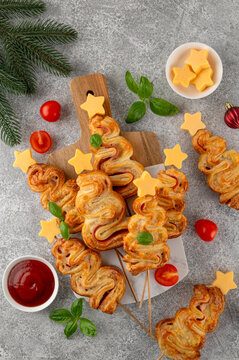 Puff pastry Christmas tree buns with cheese and ham on a board. Christmas and New Year appetizer. Top view, copy space.