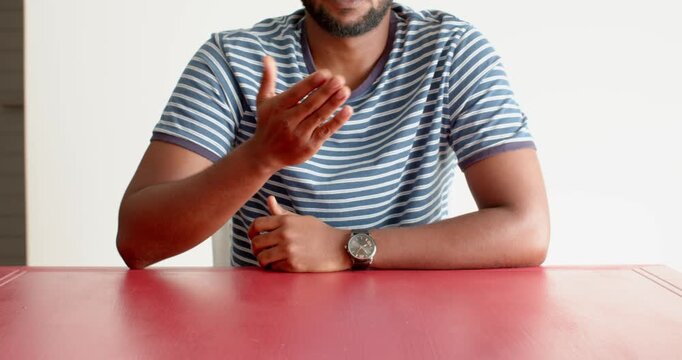Close up of people talking to the camera, gesturing with hand, man in striped shirt sitting at red t