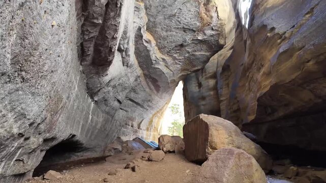Walking point of view through a narrow slot canyon with striped sandstone walls converging tightly overhead in Serra da Capivara National Park Brazil
