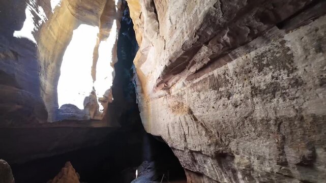 A narrow beam of sunlight pierces through a ceiling opening lighting a dark cave chamber inside Serra da Capivara National Park Brazil