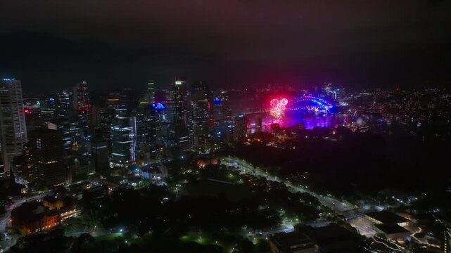 Aerial Drone View of Sydney at Night, Colourful Fireworks Exploding Over the Harbour and Illuminated City