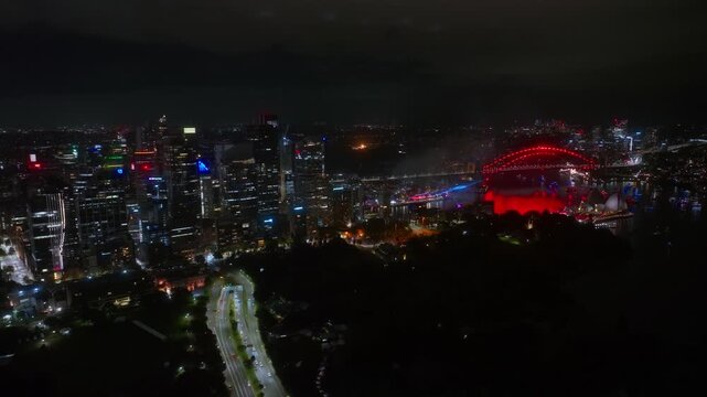 Drone View Over Sydney at Night, Fireworks Exploding Across the Harbour With City Lights and Boats Below