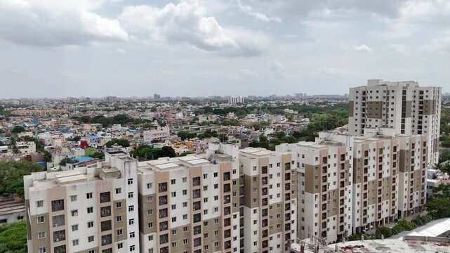 Cinematic aerial drone view of North Chennai, showcasing a large modern residential apartment complex in the foreground surrounded by a vast densely populated urban landscape.