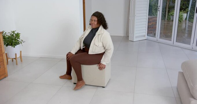 High speed photography for dynamic scenes, woman sitting on ottoman, looking down, wearing casual cl