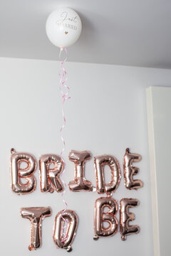 Rose gold foil balloons spelling Bride to Be with white Just Married balloon on wall for bridal shower decoration