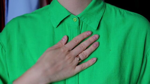 Close-up of hands fixing a collar on a vibrant green linen shirt.