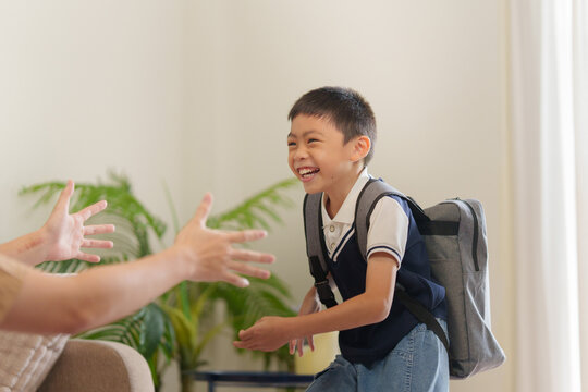 Happy Asian schoolboy with backpack running to parent at home for back to school