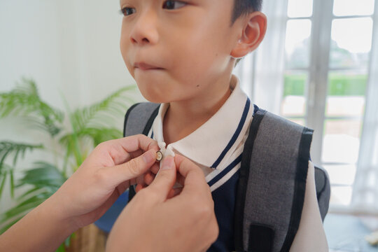 Parent helping child button uniform collar for back to school morning routine