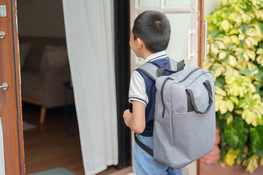 Asian student with backpack standing at doorway for back to school routine