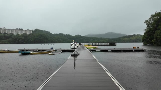 Slow POV Moving Along a Wet Pier Toward Boats on a Rainy Lake