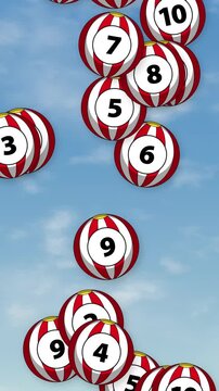 Numbered Red and White Striped Balls Falling Against Blue Sky