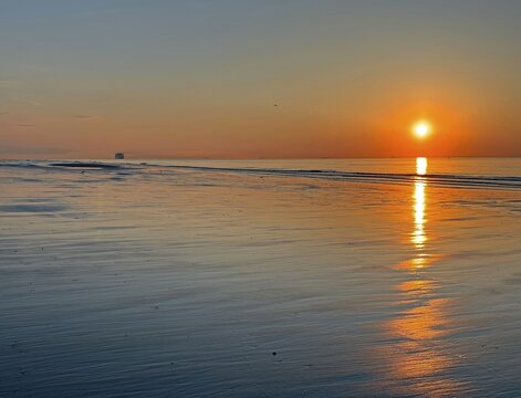 Sunset at the sea with calm water surface and orange-coloured sky, Atlantic Ocean, Calais, France