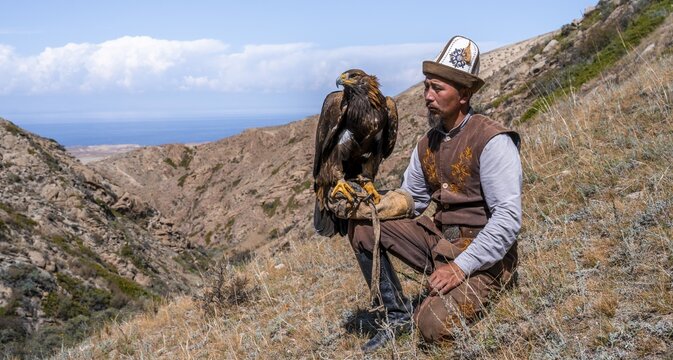 Traditional Kyrgyz eagle hunter with eagle in the mountains, hunting, near Bokonbayevo, Issyk Kul region, Kyrgyzstan