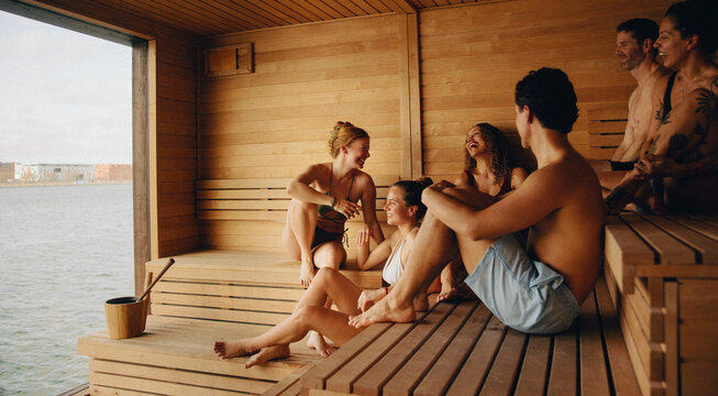 A bathhouse sauna scene shows friends enjoying wellness by the window.