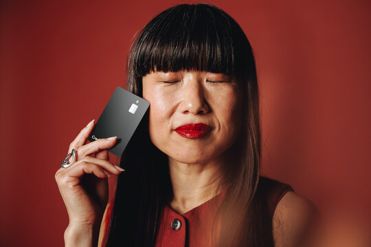 Confident woman holding black card in studio portrait for personal finance theme