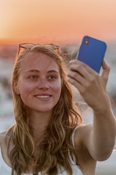 Young woman with white top photographs herself with a smartphone, selfie, sunset, Plaza de la Encarnacion, Seville, Andalusia, Spain