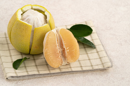 Fresh pomelo fruit with leaf on white table background.