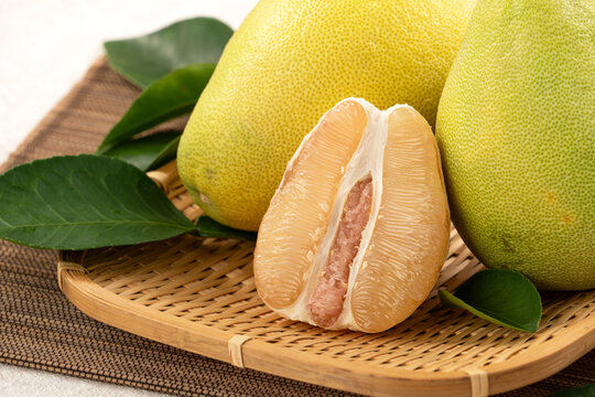 Fresh pomelo fruit with leaf on white table background.