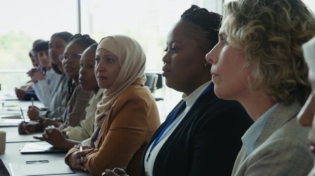 A group of focused business women listen intently during a conference or seminar. Their engaged expressions show their dedication to learning and collaboration in a professional setting.