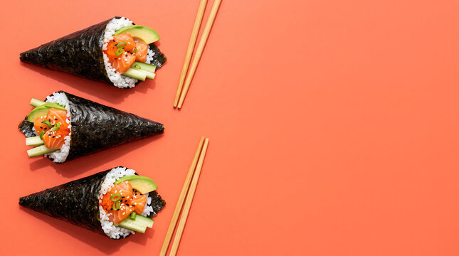 Temaki hand rolls with salmon and avocado on coral background